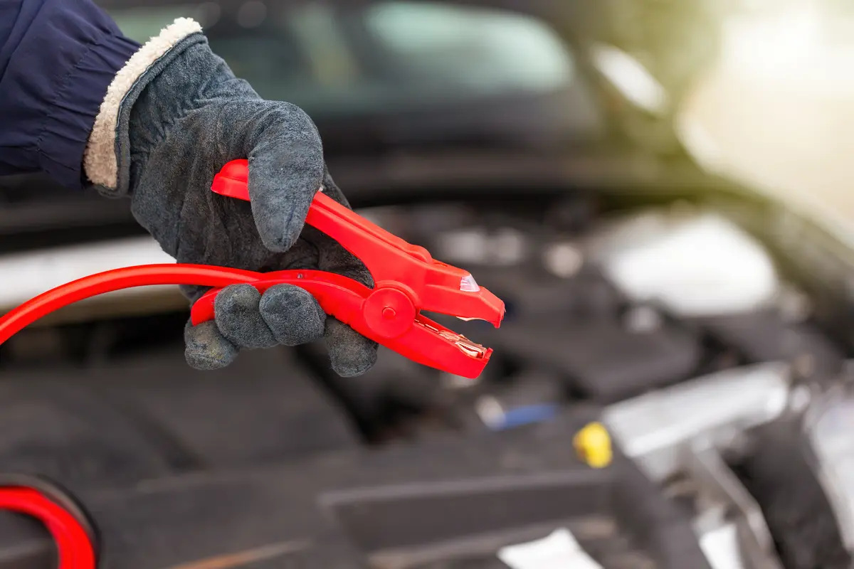 Recovery technician holding jump leads over a car engine for a jump start